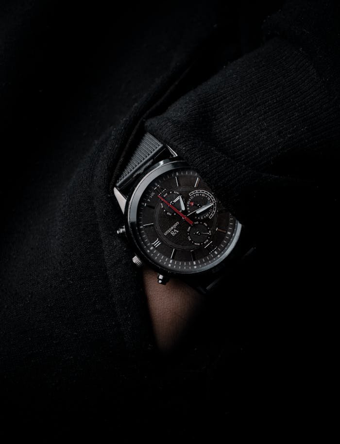 Close-up of a stylish black wristwatch partially hidden in knitwear, showcasing time and elegance.