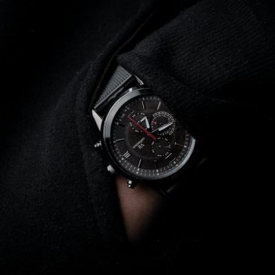 Close-up of a stylish black wristwatch partially hidden in knitwear, showcasing time and elegance.